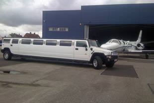 Hummer limo stands next to charter jet