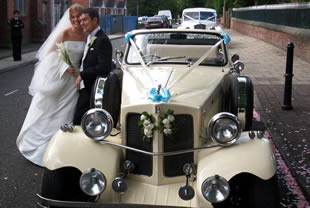 Groom stands next to wedding car in Bolton, Lancs